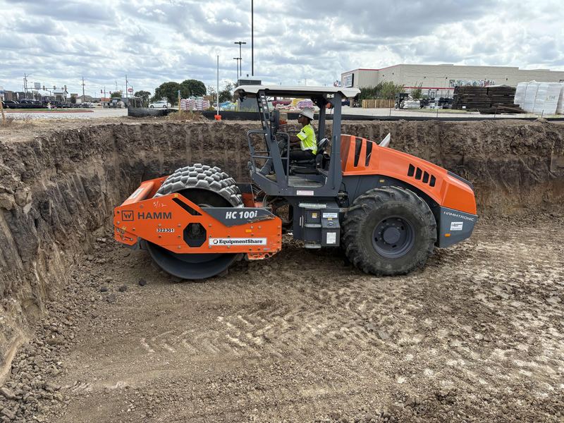 Smooth-drum roller working the floor of a large commercial excavation
