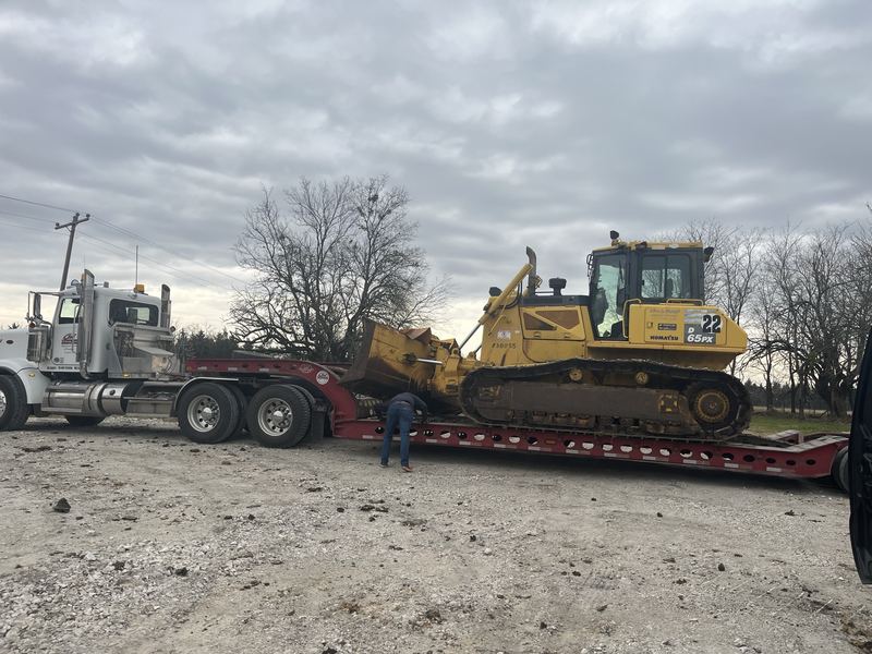 Dozer loaded on a lowboy trailer behind a semi truck